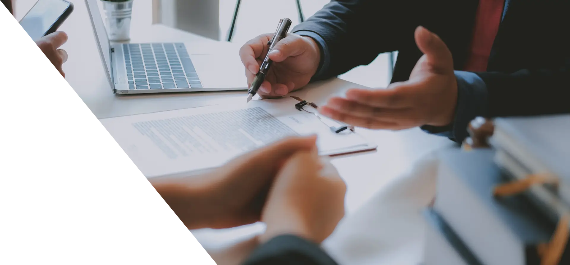 someone is signing a document with a pen and a laptop