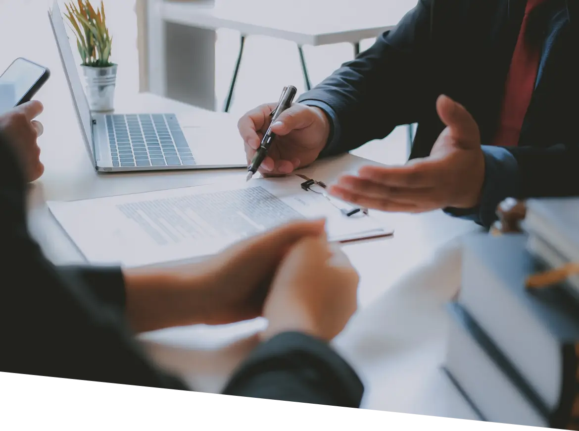 two people sitting at a table with papers and laptops